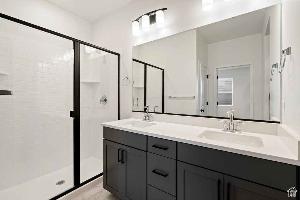 Bathroom featuring a shower with shower door, oversized vanity, and dual sinks