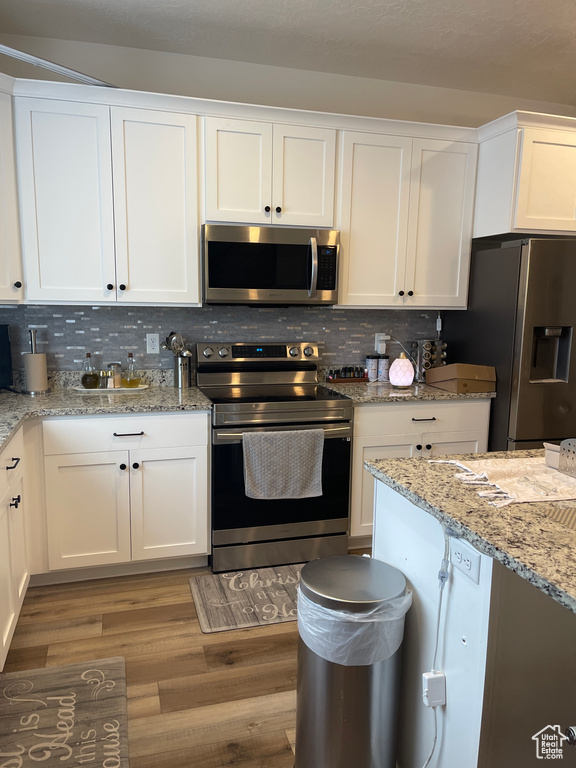 Kitchen featuring appliances with stainless steel finishes, light hardwood / wood-style flooring, and white cabinetry