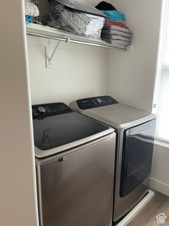 Clothes washing area featuring washing machine and clothes dryer and dark wood-type flooring