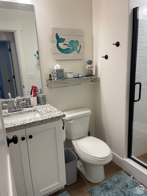 Bathroom with an enclosed shower, vanity, hardwood / wood-style flooring, and toilet