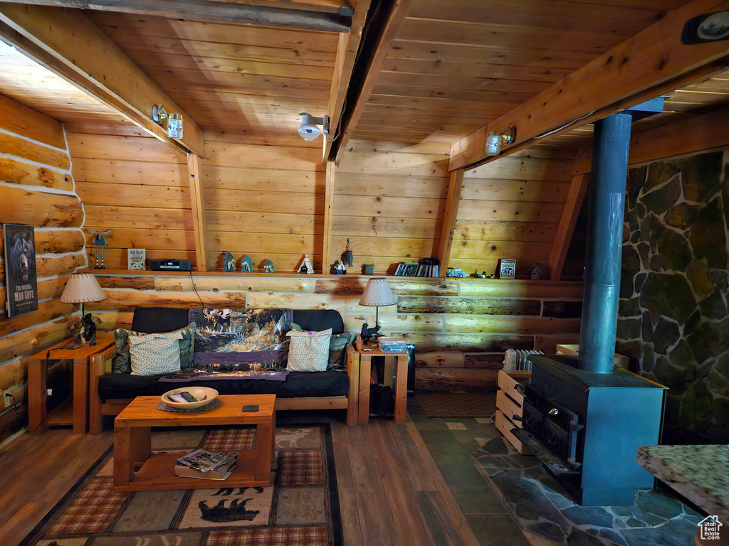 Living room with dark hardwood / wood-style flooring, log walls, wood ceiling, and a wood stove