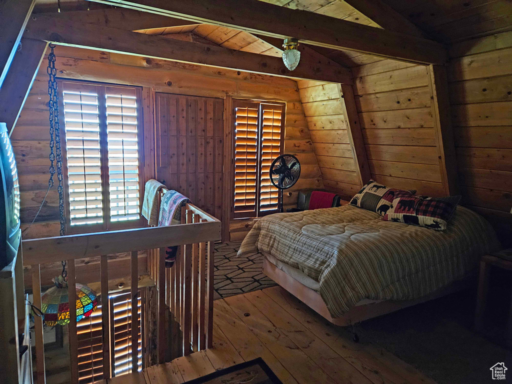 Bedroom with vaulted ceiling with beams, wood ceiling, multiple windows, and wood-type flooring