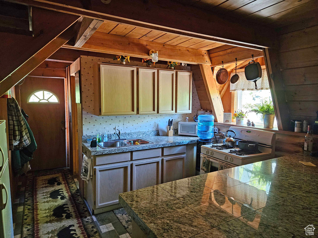 Kitchen featuring white appliances, wood ceiling, tile floors, wooden walls, and sink