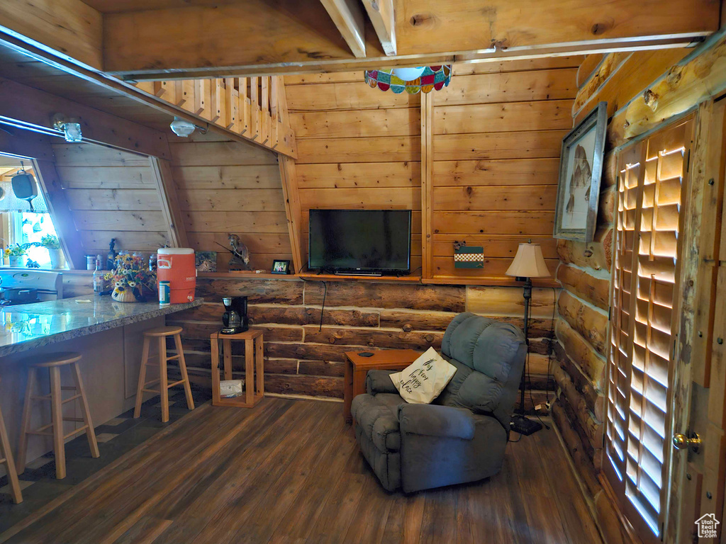 Living room featuring dark hardwood / wood-style floors, wooden walls, and log walls