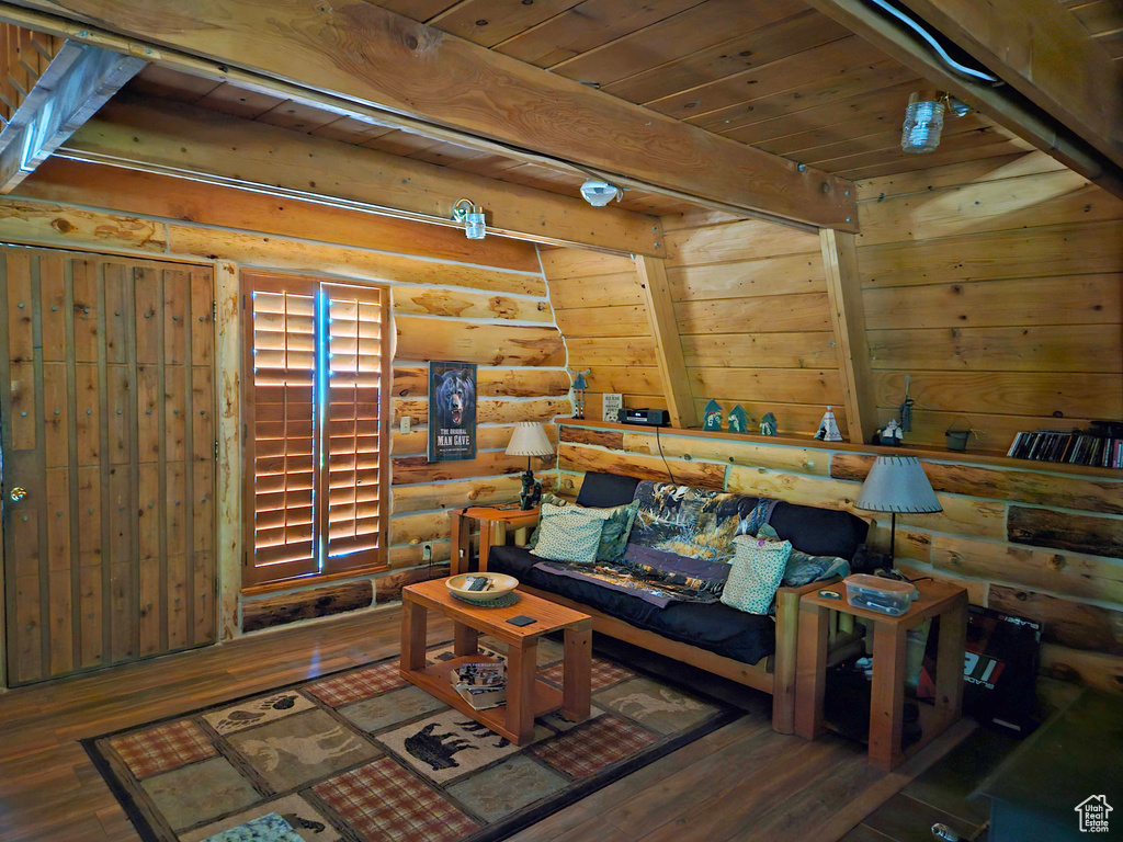 Living room featuring dark hardwood / wood-style floors, beam ceiling, log walls, and wood ceiling