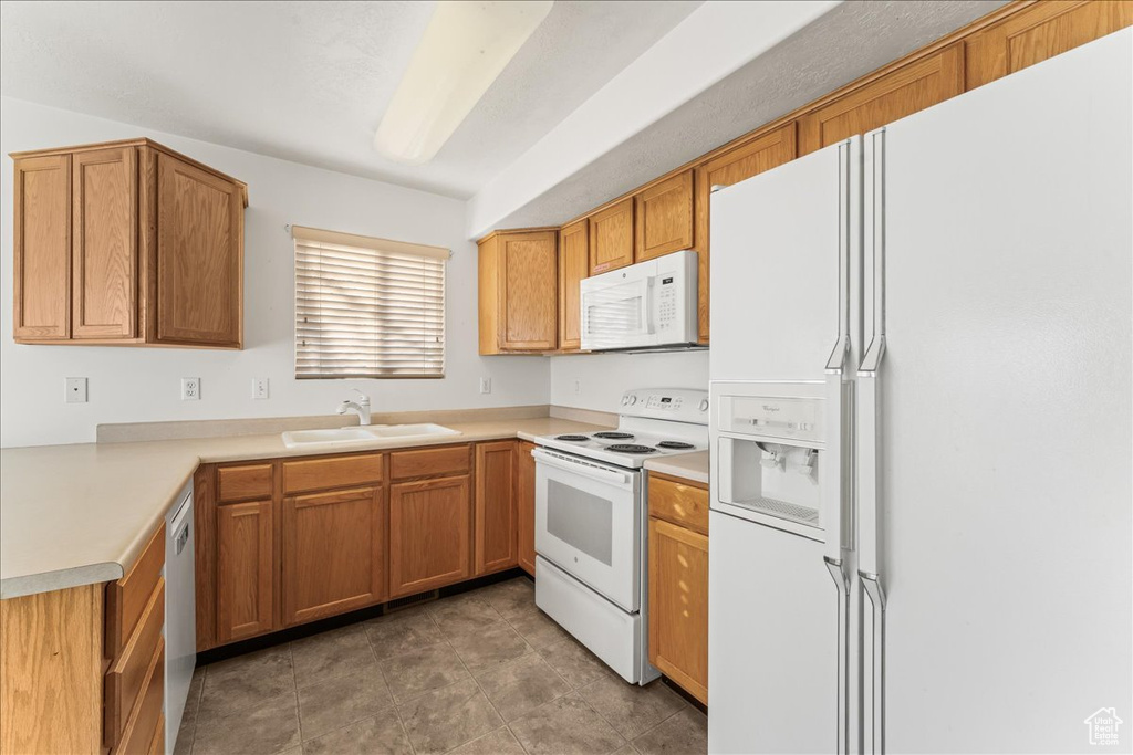 Kitchen featuring sink, dark tile flooring, and white appliances