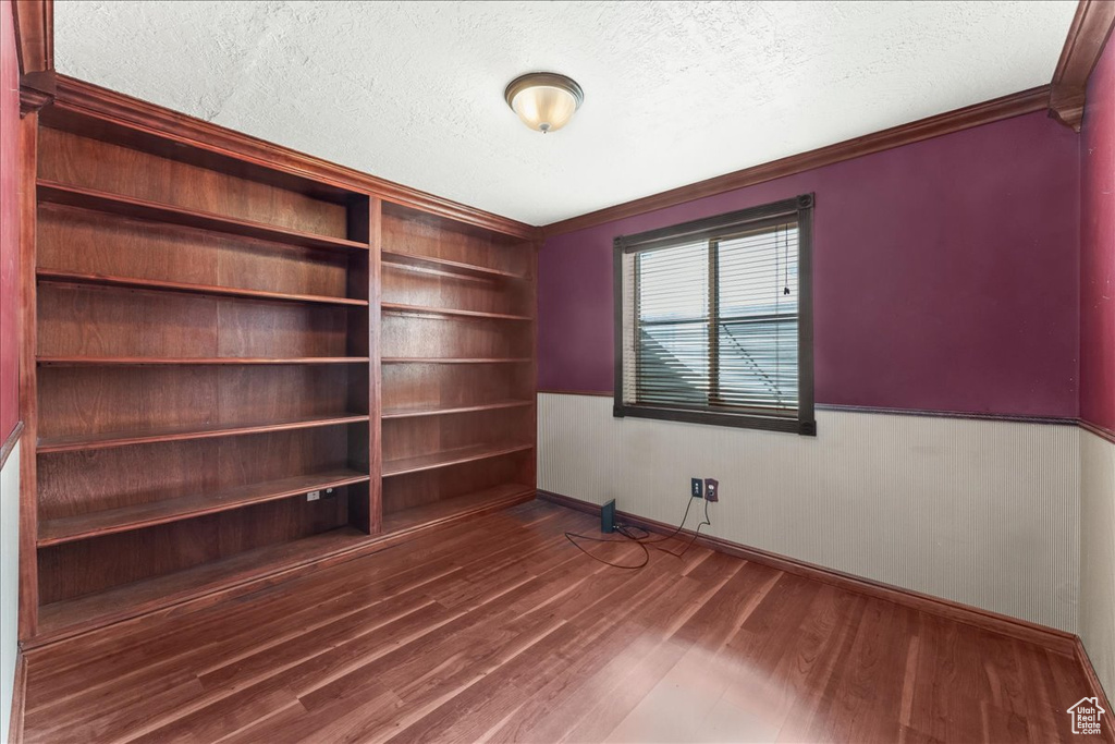 Spare room with a textured ceiling, dark hardwood / wood-style flooring, and ornamental molding