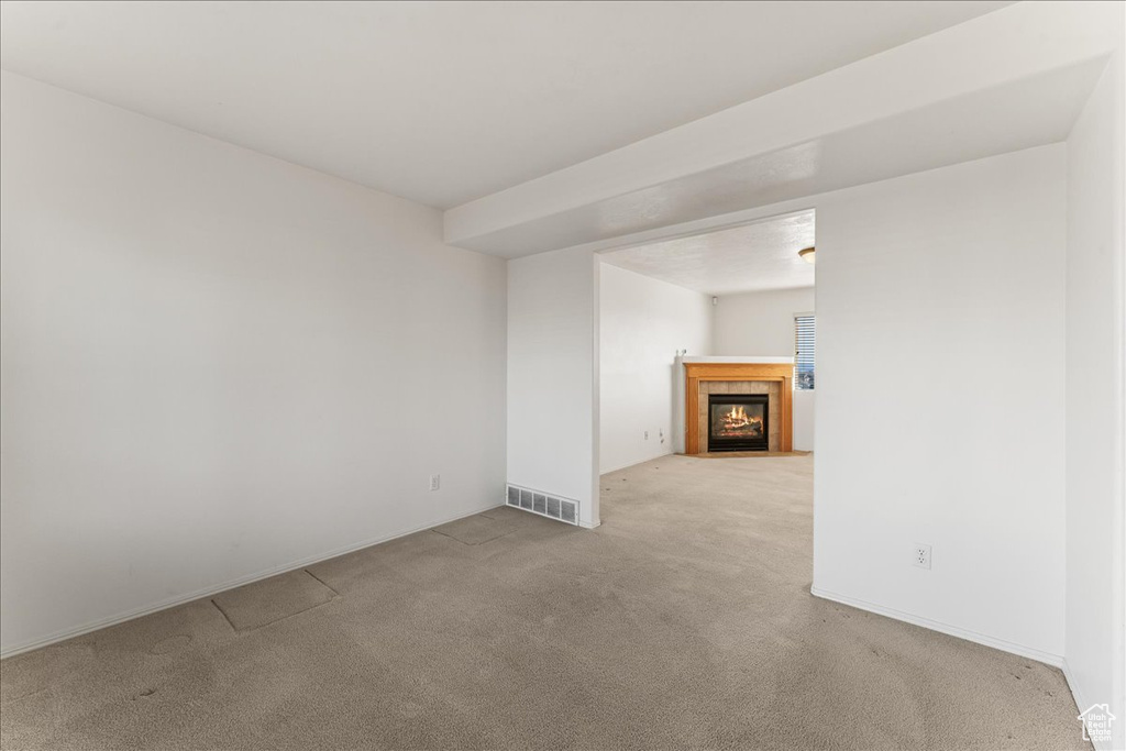 Unfurnished living room featuring light carpet and a tile fireplace