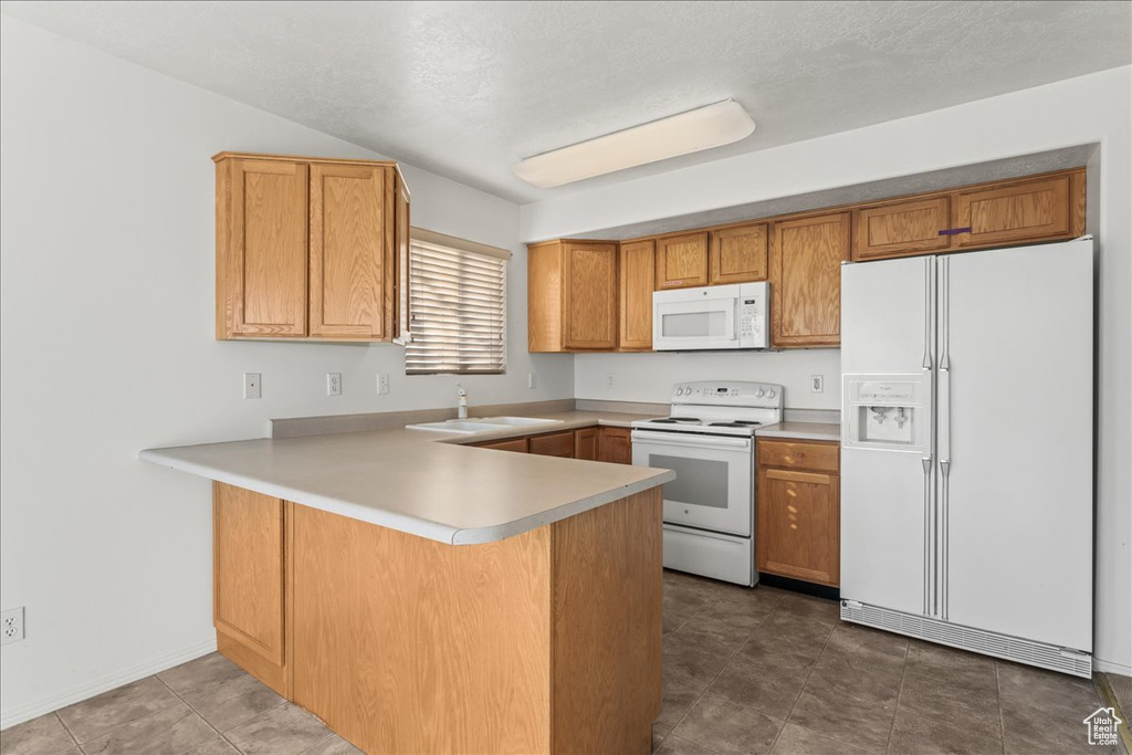 Kitchen with tile flooring, white appliances, and kitchen peninsula