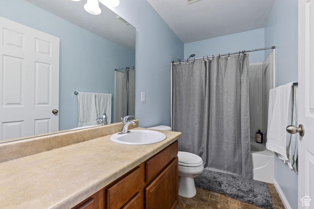 Full bathroom featuring toilet, vanity, and shower / bath combination with curtain