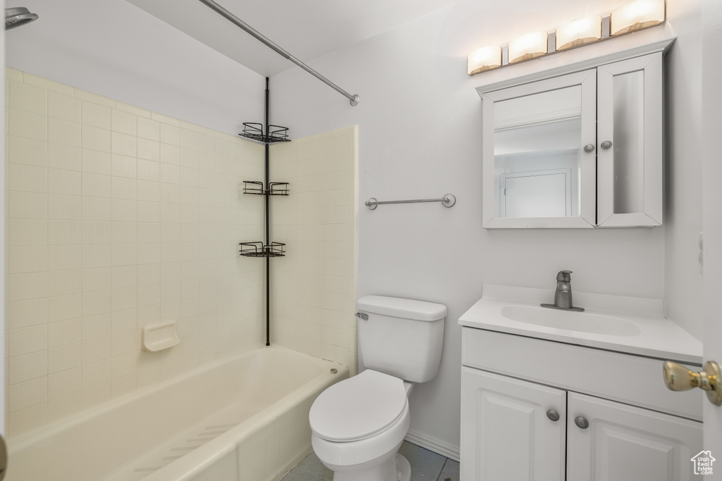 Full bathroom featuring tile floors, large vanity, toilet, and tiled shower / bath