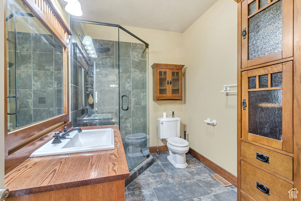 Bathroom with an enclosed shower, tile flooring, toilet, and vanity with extensive cabinet space