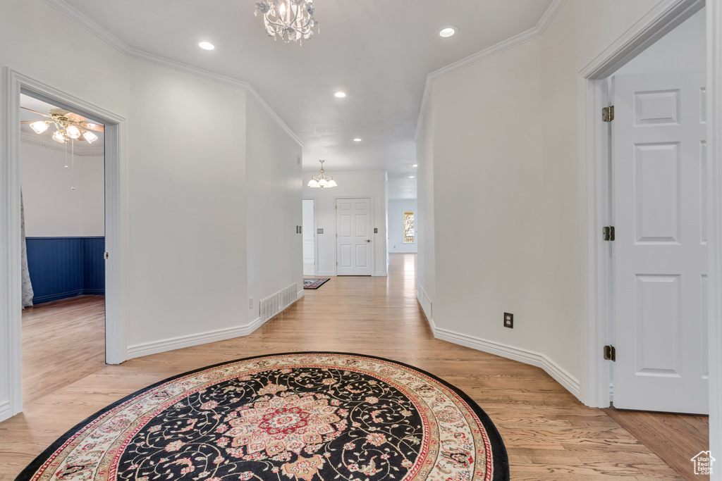 Entrance foyer featuring an inviting chandelier, ornamental molding, and light hardwood / wood-style floors
