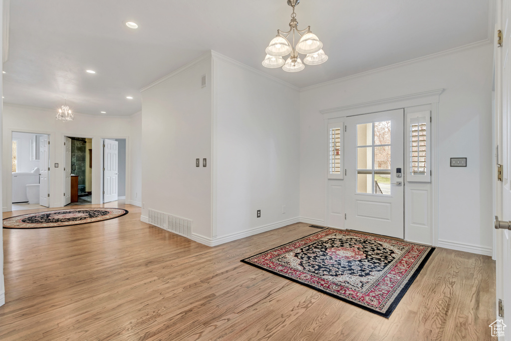 Entryway featuring crown molding, light hardwood / wood-style floors, and a notable chandelier