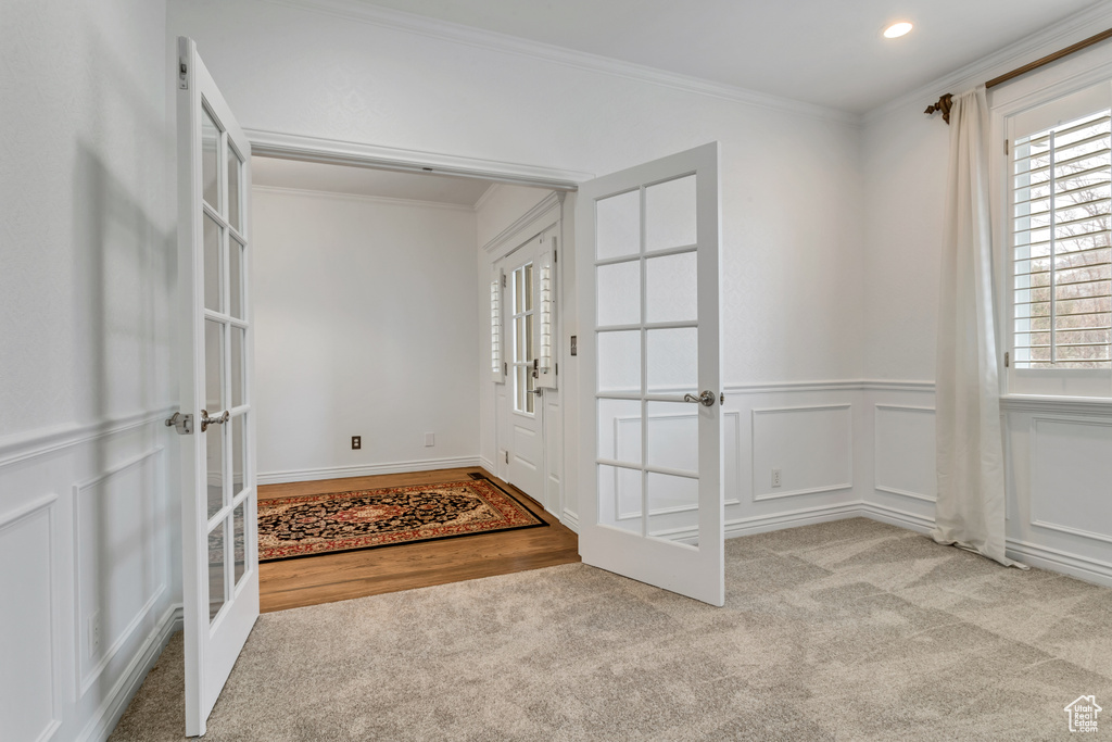 Carpeted foyer entrance with ornamental molding and french doors