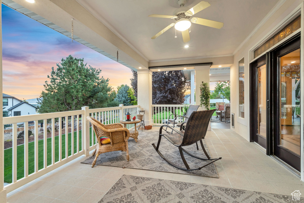 Patio terrace at dusk featuring a lawn and ceiling fan