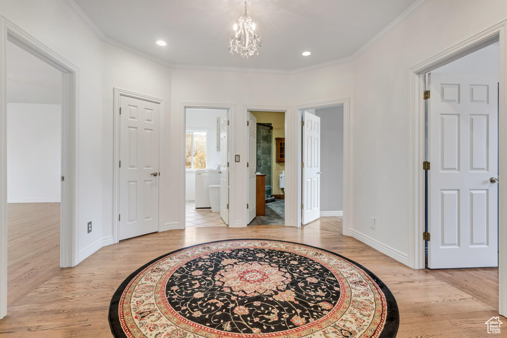 Entrance foyer with an inviting chandelier, crown molding, and light hardwood / wood-style flooring
