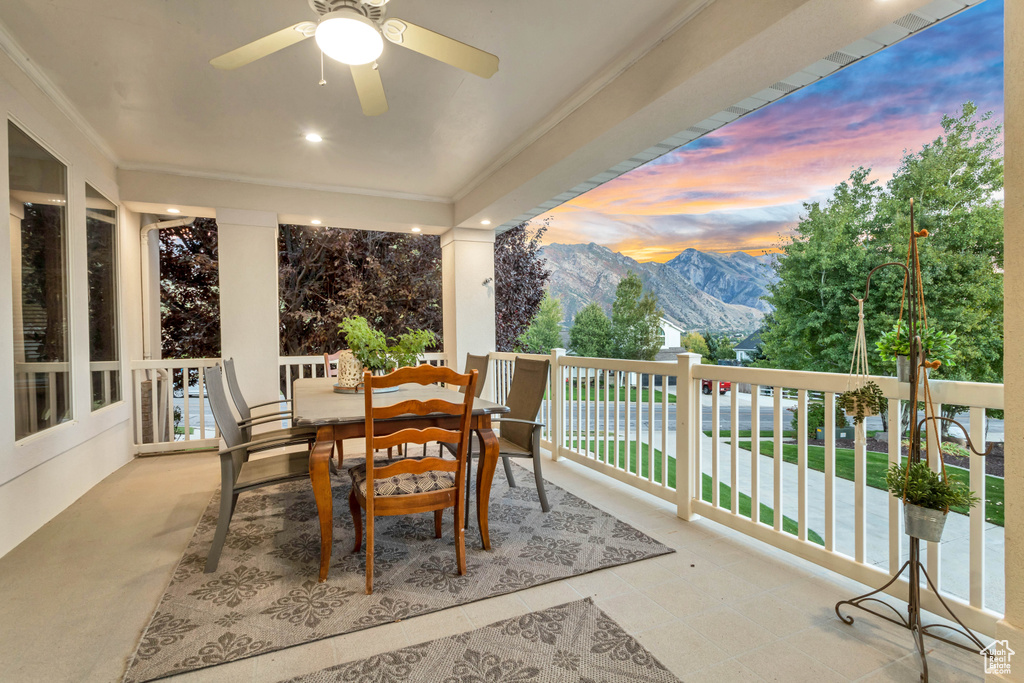 Patio terrace at dusk featuring a mountain view, a balcony, and ceiling fan