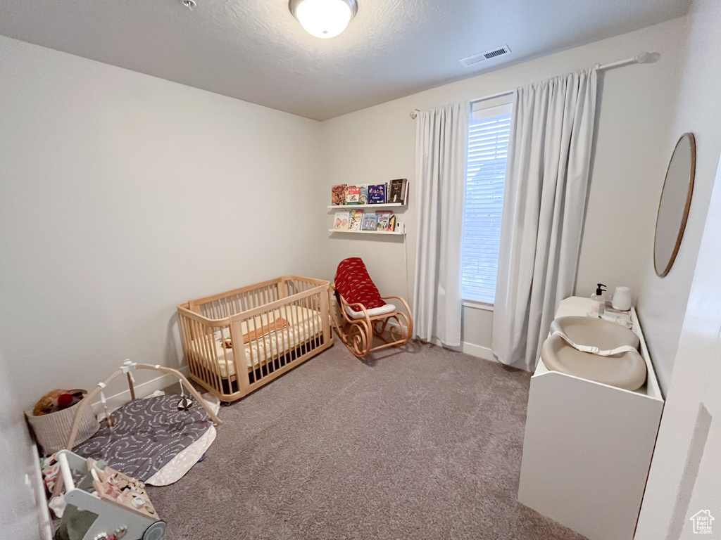 Bedroom with multiple windows, a nursery area, and carpet floors