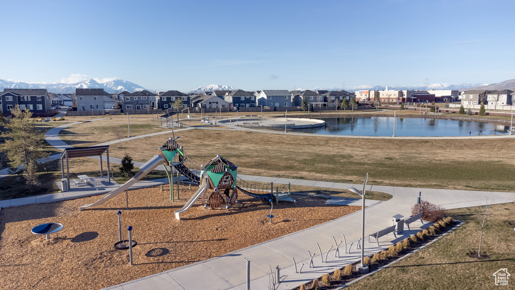 View of property's community featuring a water view, a playground, and a lawn