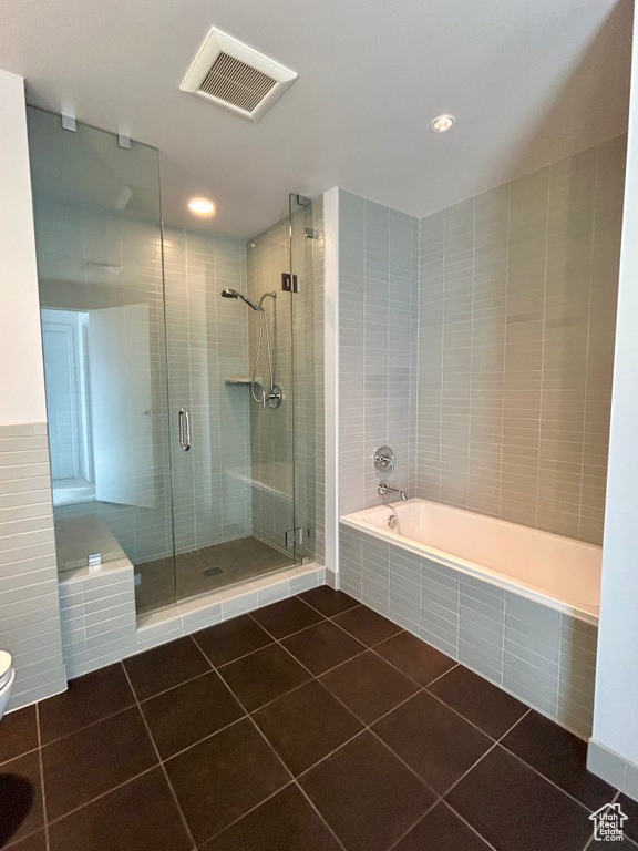 Bathroom with toilet, tile flooring, and shower with separate bathtub