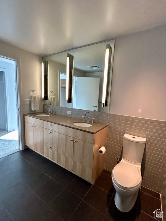 Bathroom featuring tile floors, double sink, vanity with extensive cabinet space, and tile walls