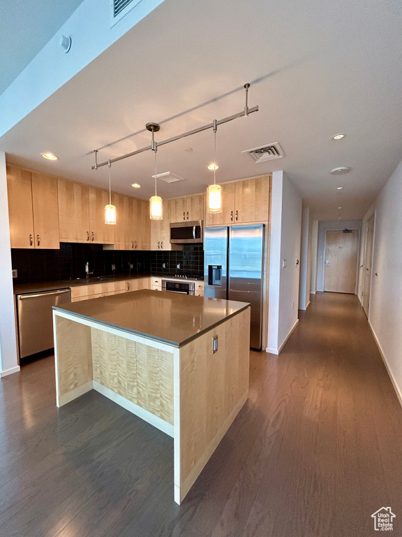 Kitchen featuring dark hardwood / wood-style flooring, a kitchen island, stainless steel appliances, decorative light fixtures, and backsplash