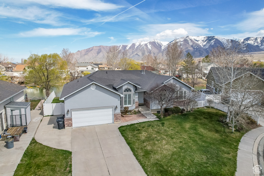 Ranch-style home with a mountain view, a front yard, and a garage