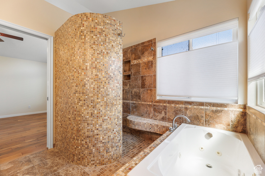 Bathroom with tile walls, hardwood / wood-style flooring, a healthy amount of sunlight, and ceiling fan
