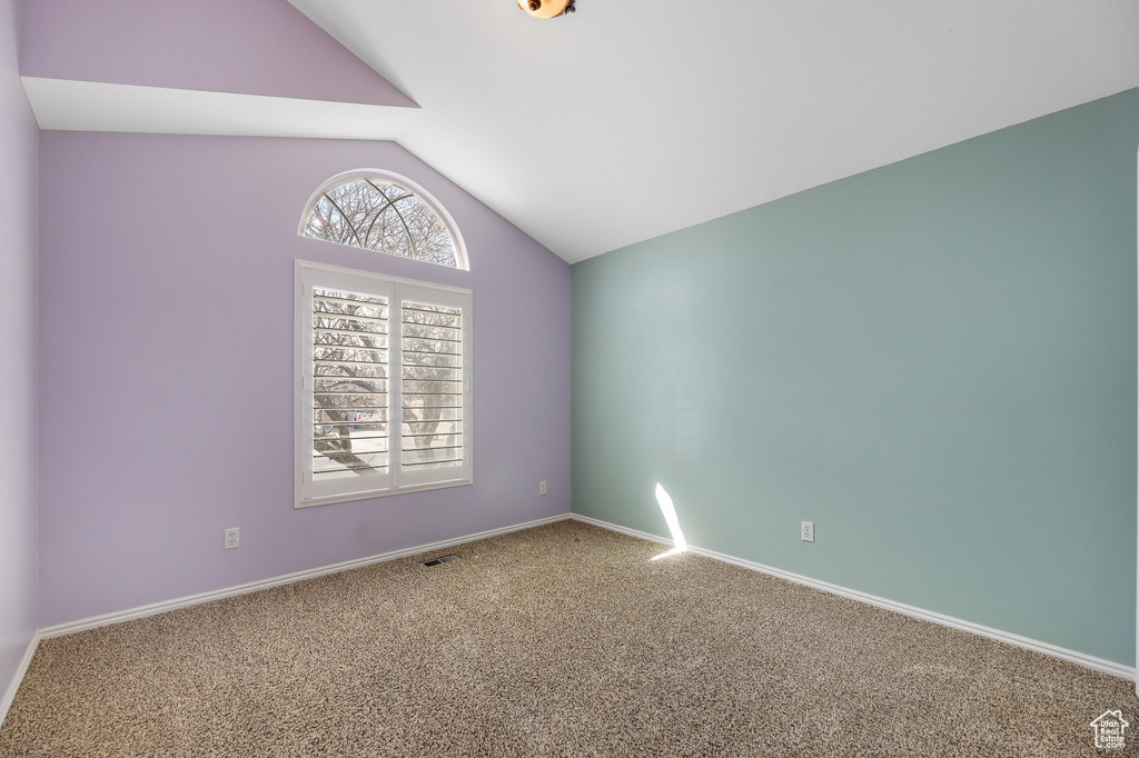 Empty room featuring lofted ceiling and carpet flooring
