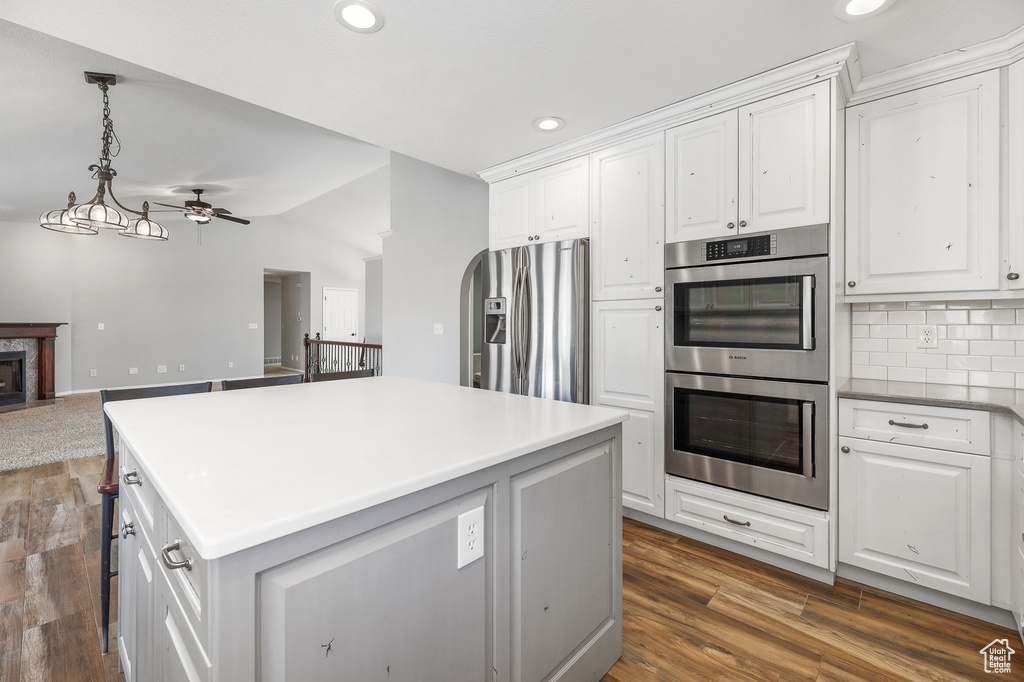 Kitchen featuring dark wood-type flooring, white cabinets, appliances with stainless steel finishes, and a kitchen island