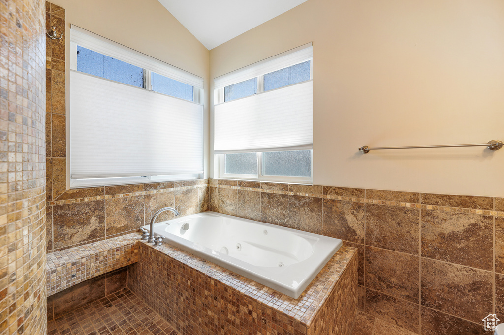 Bathroom with vaulted ceiling, tile floors, and a relaxing tiled bath