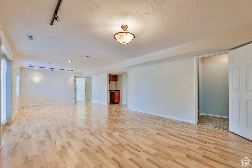 Unfurnished room with light hardwood / wood-style flooring and track lighting