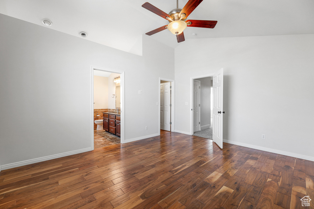 Unfurnished bedroom with high vaulted ceiling, ceiling fan, connected bathroom, and dark hardwood / wood-style floors