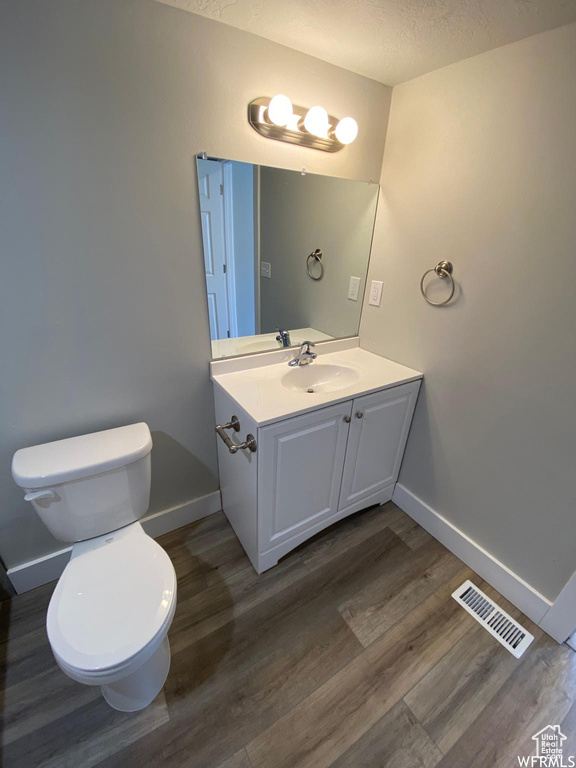 Bathroom with vanity, hardwood / wood-style flooring, toilet, and a textured ceiling