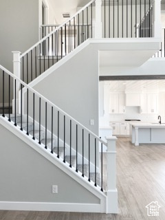 Staircase with a high ceiling, sink, and light hardwood / wood-style floors
