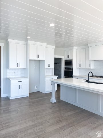 Kitchen featuring tasteful backsplash and white cabinetry