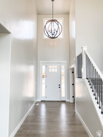 Foyer entrance featuring a towering ceiling, an inviting chandelier, and dark hardwood / wood-style flooring