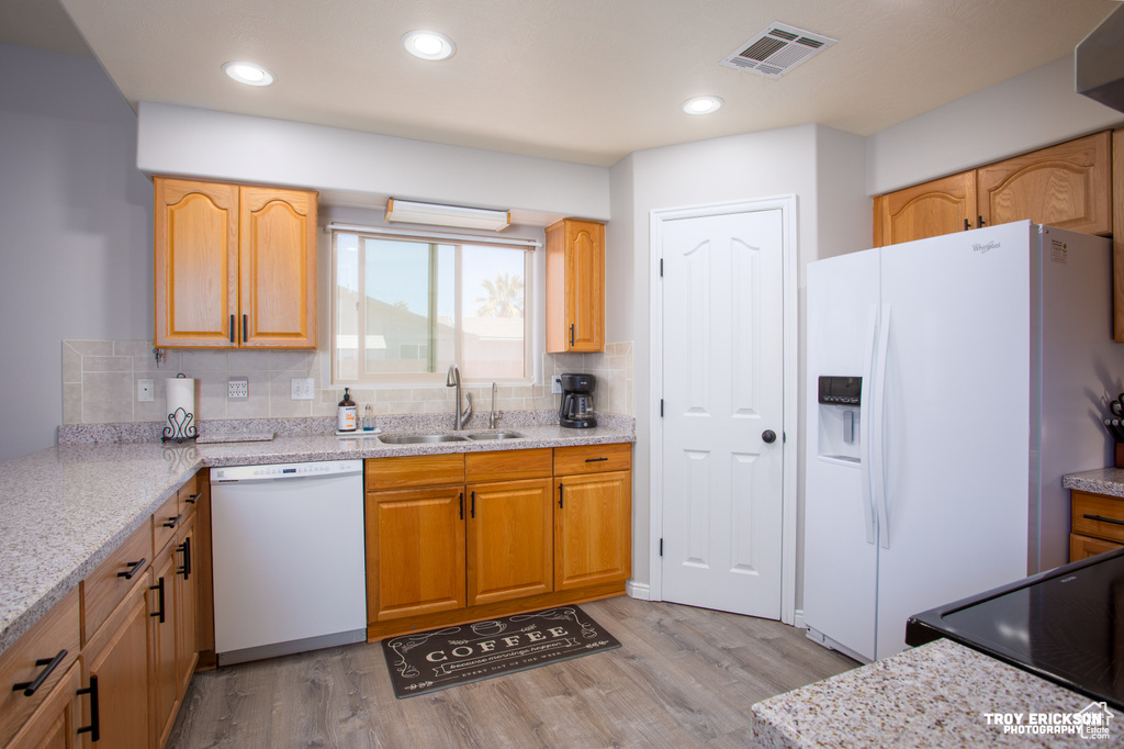 Kitchen with tasteful backsplash, sink, light hardwood / wood-style flooring, and white appliances