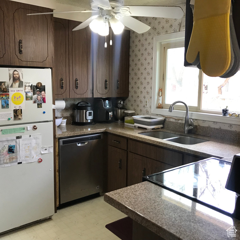 Kitchen featuring dark brown cabinets, white fridge, light tile floors, sink, and dishwasher