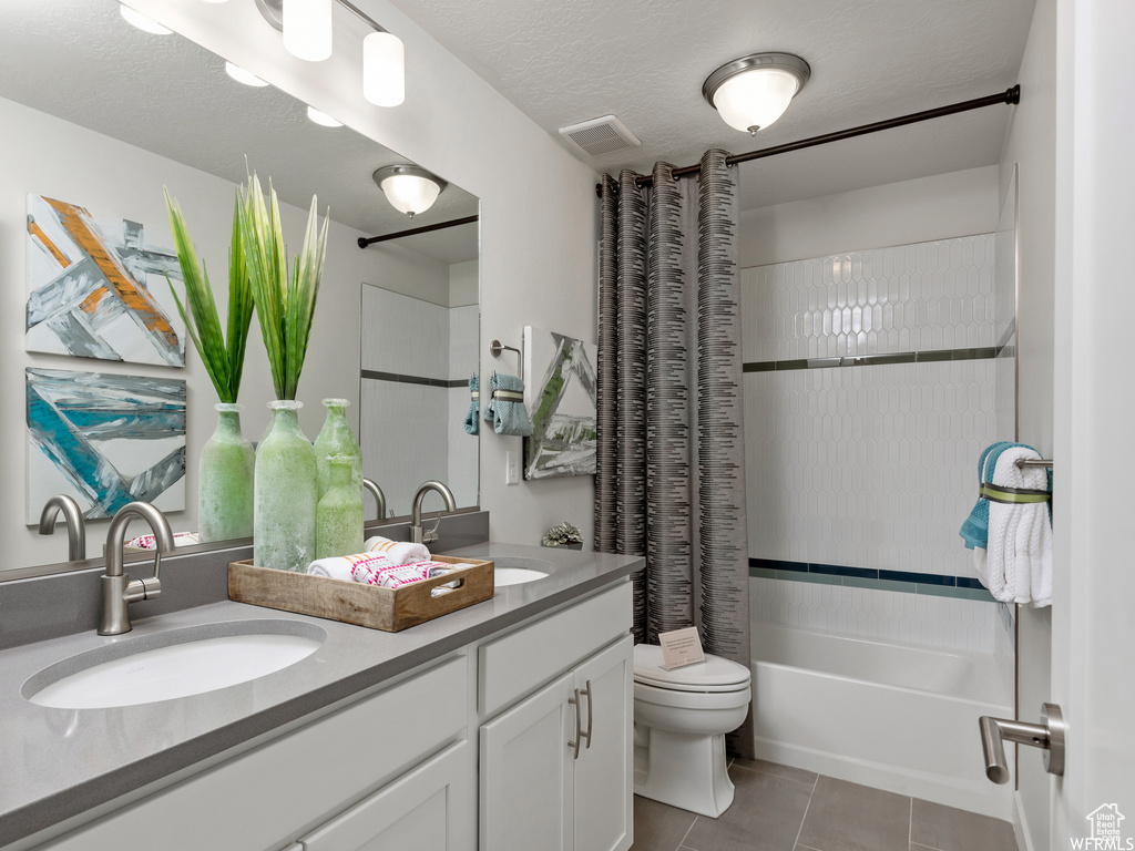 Full bathroom with dual sinks, tile flooring, oversized vanity, shower / tub combo, and toilet