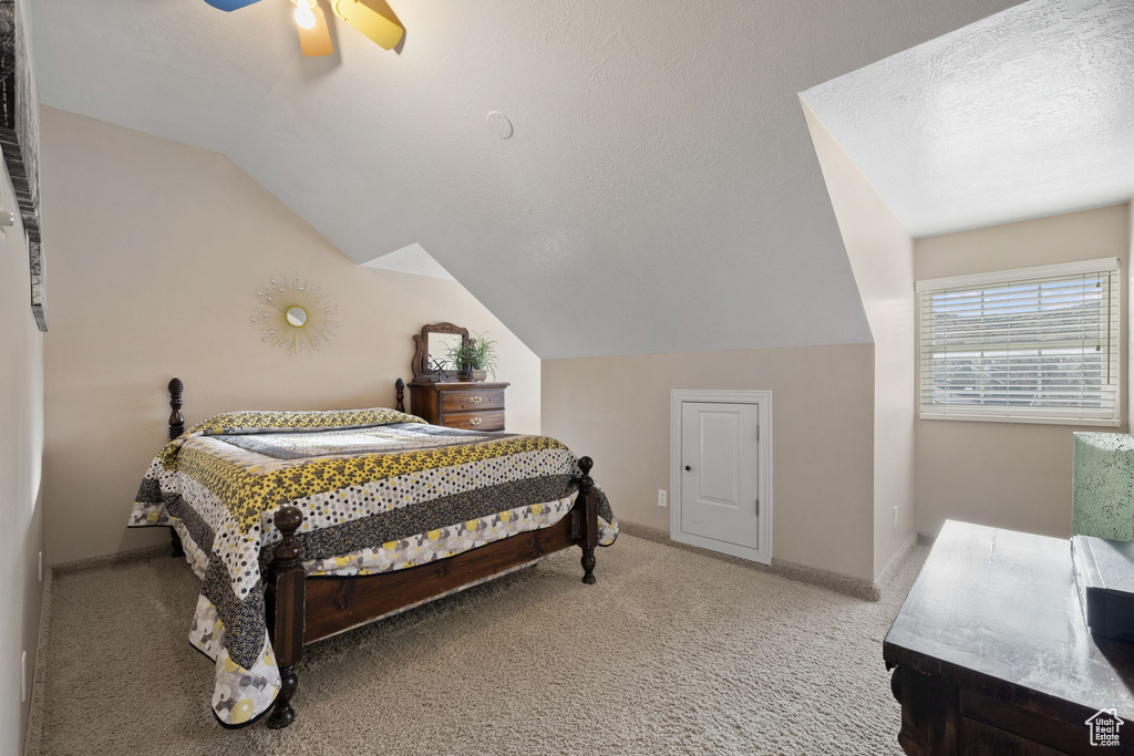 Bedroom with light carpet, lofted ceiling, ceiling fan, and a textured ceiling