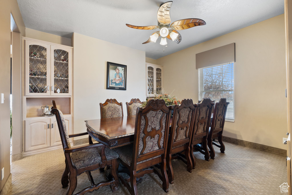 Carpeted dining space with ceiling fan