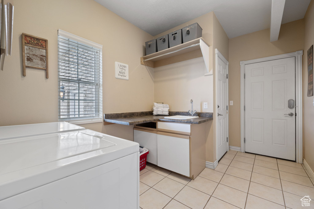 Kitchen featuring light tile floors, sink, white cabinetry, and independent washer and dryer