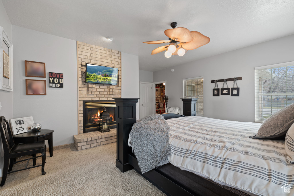 Carpeted bedroom featuring brick wall, a closet, a brick fireplace, and ceiling fan
