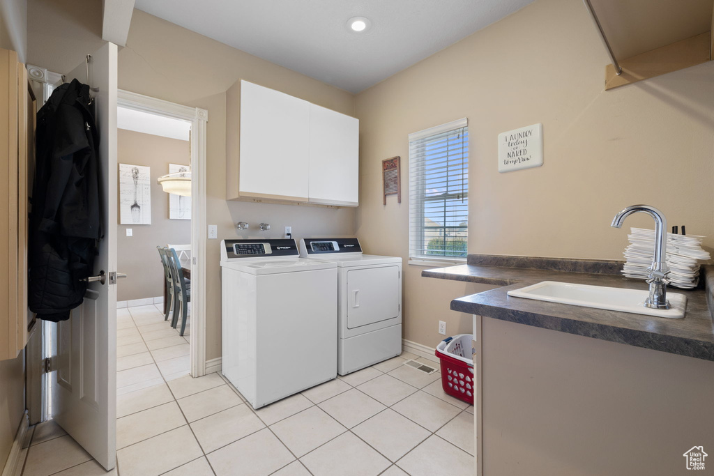 Laundry room featuring washing machine and clothes dryer, cabinets, sink, and light tile floors