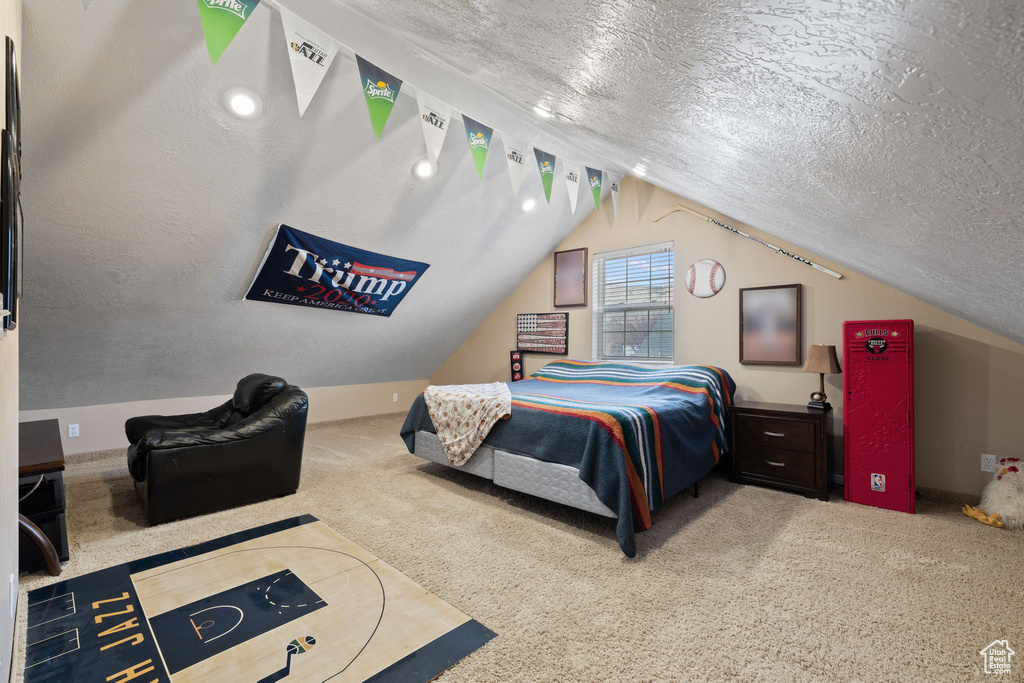 Bedroom featuring a textured ceiling, lofted ceiling, and light colored carpet