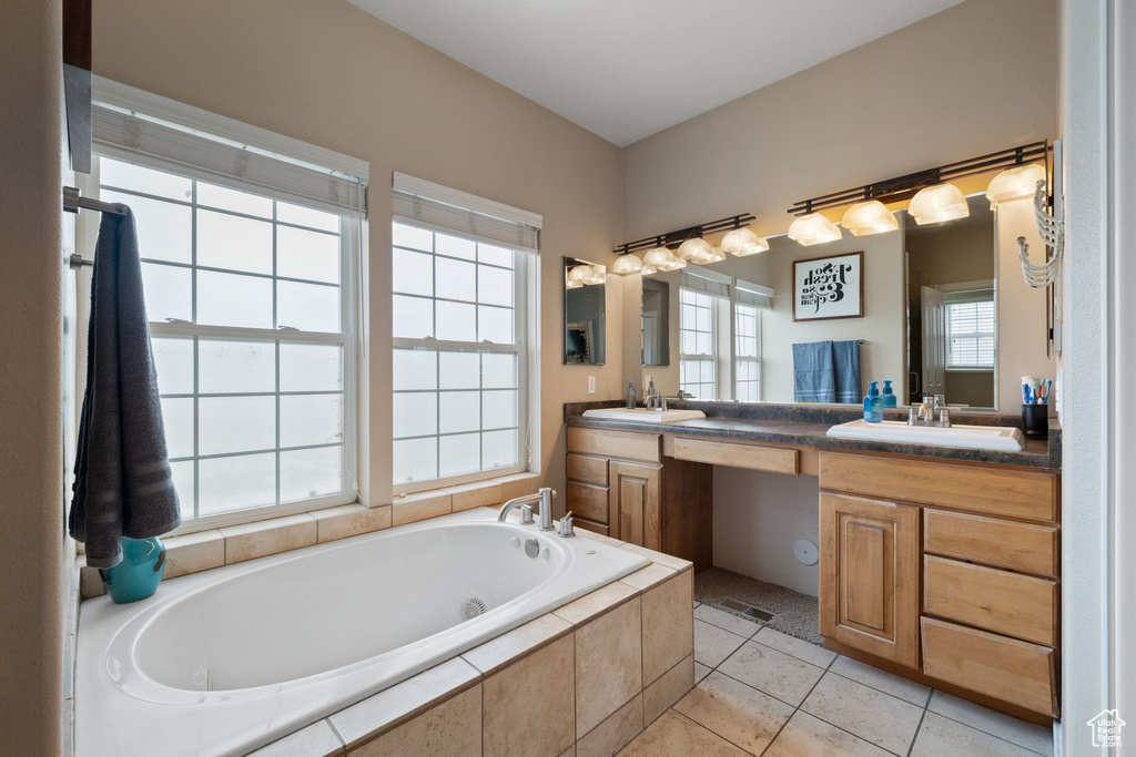 Bathroom with tiled tub, dual vanity, and tile flooring