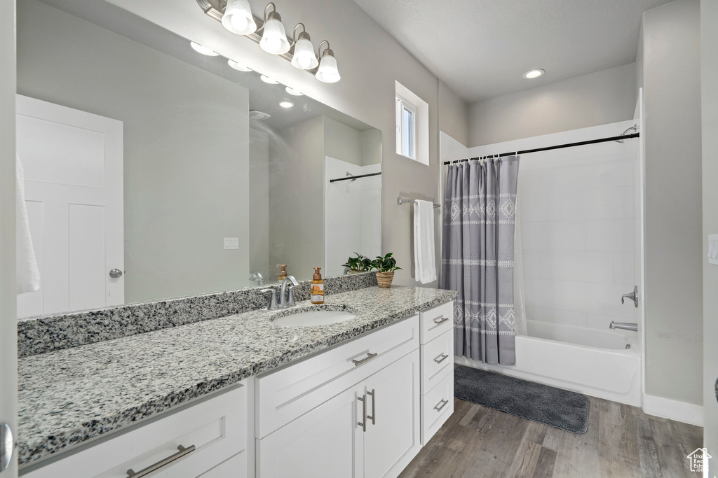 Bathroom featuring vanity, shower / tub combo with curtain, and hardwood / wood-style flooring