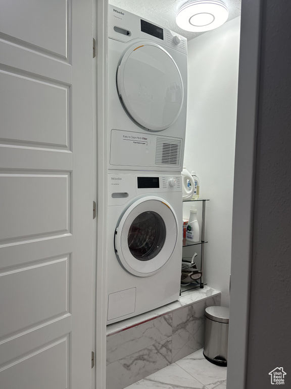 Laundry area with tile floors and stacked washer / drying machine